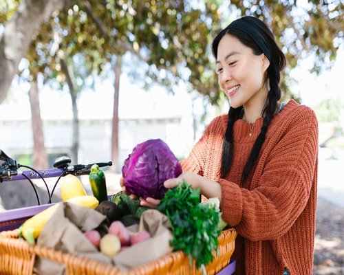 Woman holding a basket of fresh vegetables at a local market